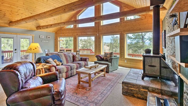 A spacious living room with a fireplace, leather sofas, and large windows.