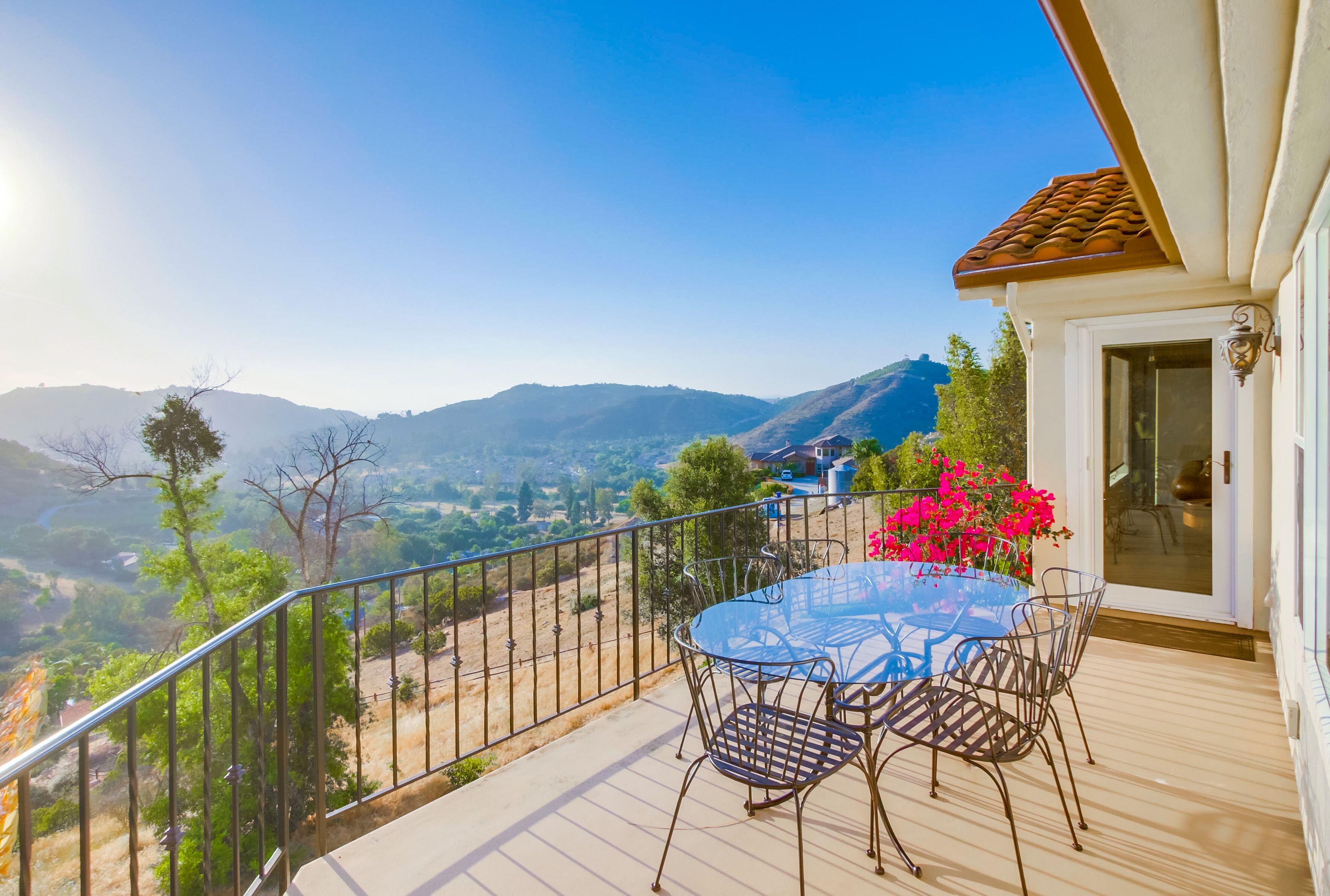 Un balcon avec une table et des chaises, donnant sur un paysage montagneux.