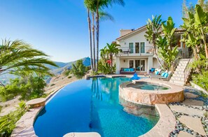 A luxurious pool area with a hot tub, lounge chairs, and a view of the mountains.