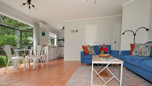 Ein modernes Wohnzimmer mit einem blauen Sofa, weißen Sesseln und einem Couchtisch.