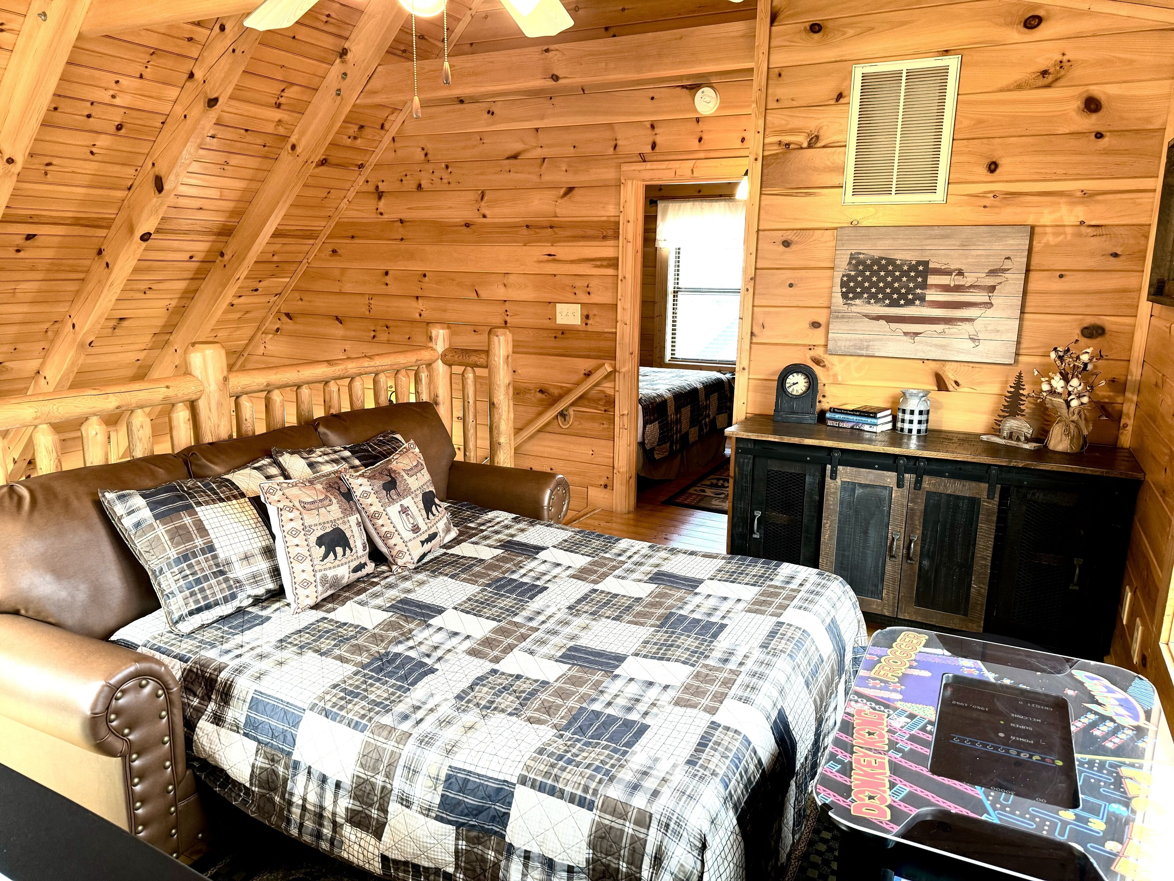 A cozy log cabin bedroom with a bed, a wooden headboard, a dresser, and a window.