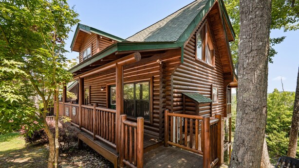 Une cabane en rondins avec un porche, des rampes en bois et une terrasse.