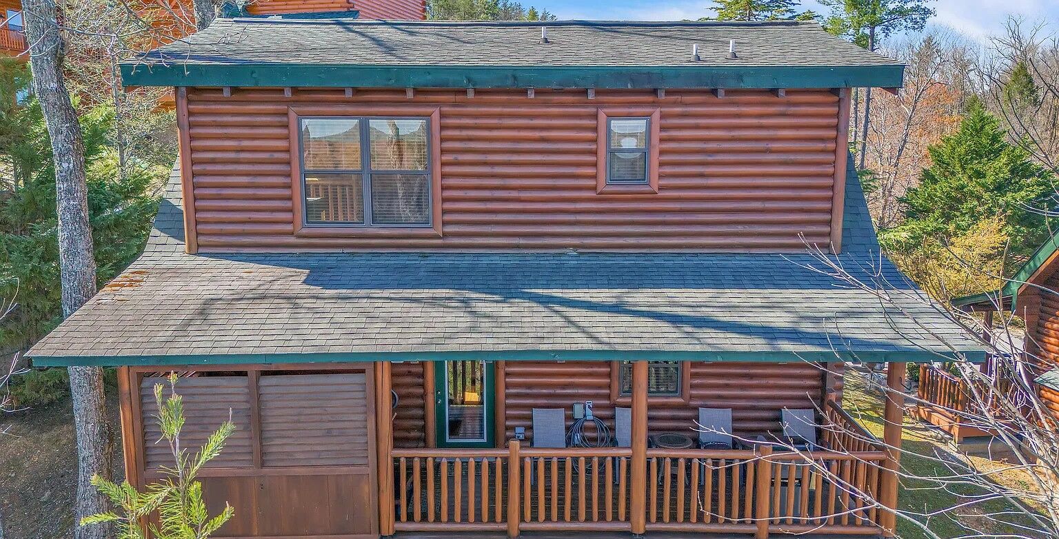 Eine zweistöckige Holzhütte mit Balkon und überdachter Veranda.