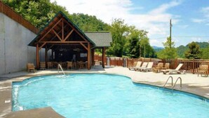 Une piscine avec des chaises longues et un pavillon en bois.