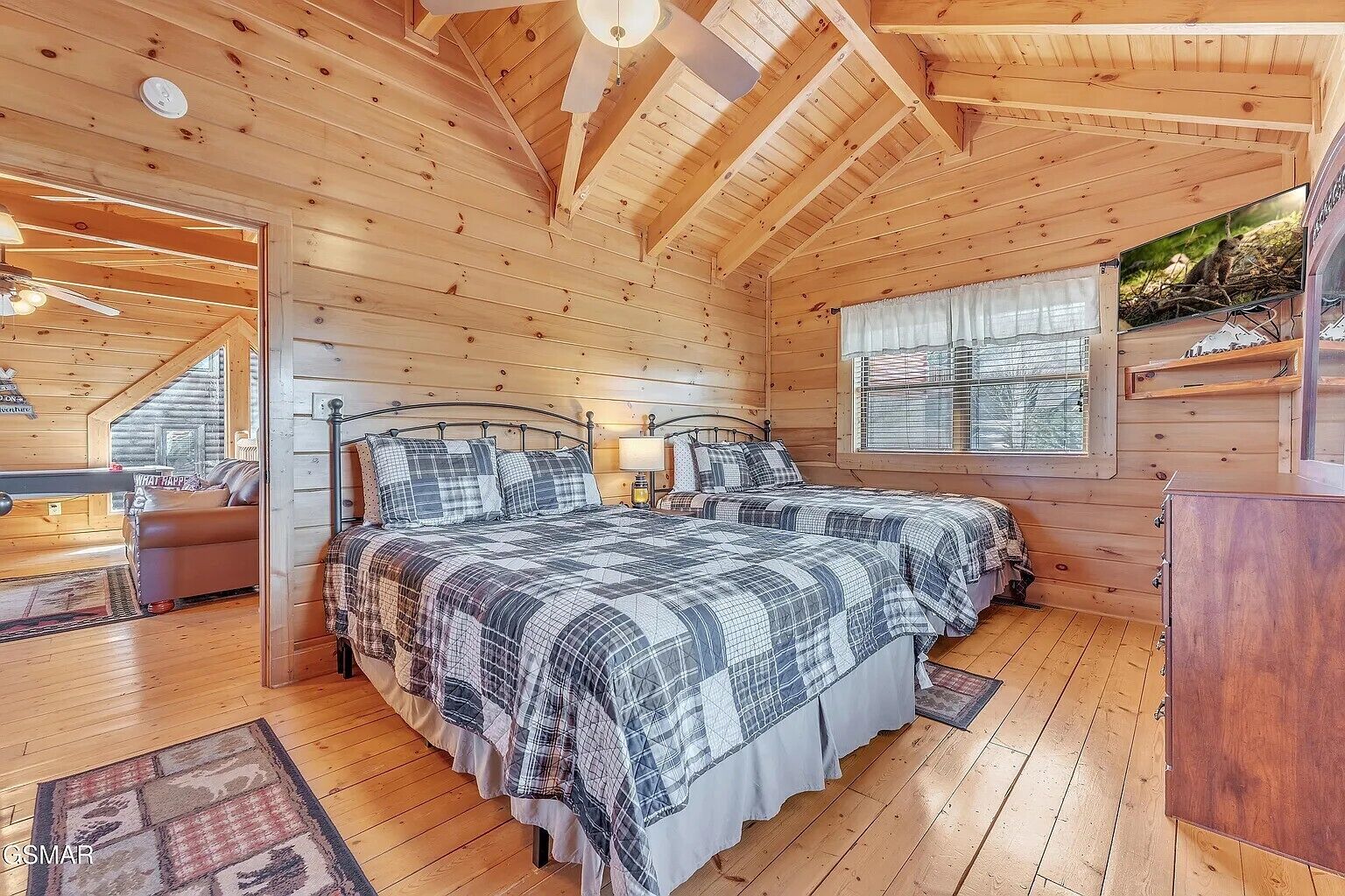 Een houten slaapkamer met twee bedden, een bank, een televisie en een raam met uitzicht.