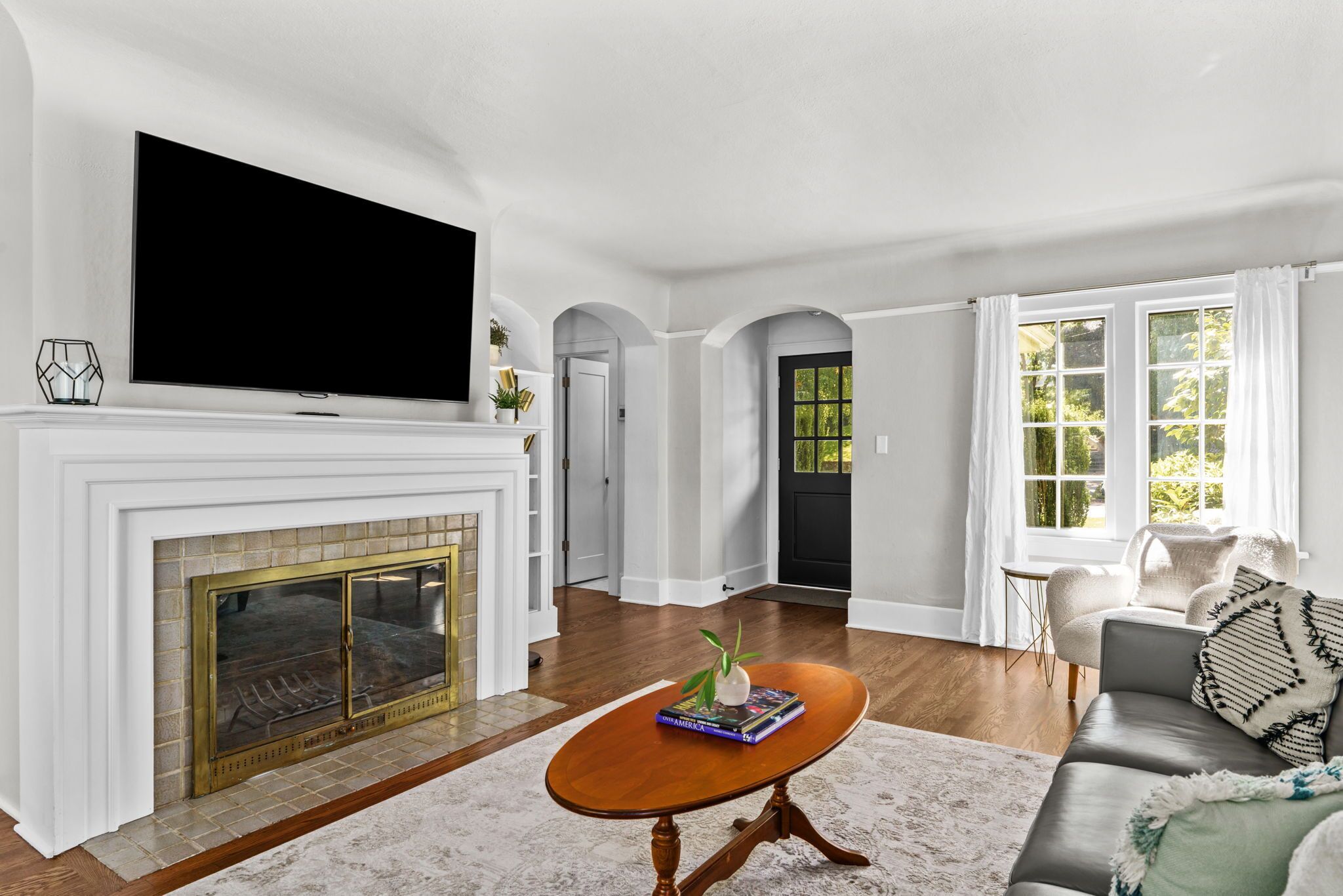A living room with a fireplace, a flat-screen TV mounted above it, a sofa, and a coffee table.