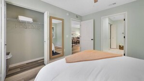 Una camera da letto con un letto grande, una cabina armadio, uno specchio e una ventola a soffitto.