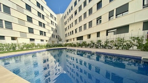 A swimming pool surrounded by a modern building with multiple floors and balconies. - Nuevo, con Grande Terraza, a 200 m de la Playa y 500m del Puerto y Centro (Cambrils)