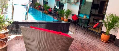 An indoor pool area with a seating area, potted plants, and air conditioning units.