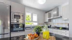 Een moderne keuken met roestvrijstalen apparatuur, een groot raam en een ontbijtarrangement op het aanrecht.