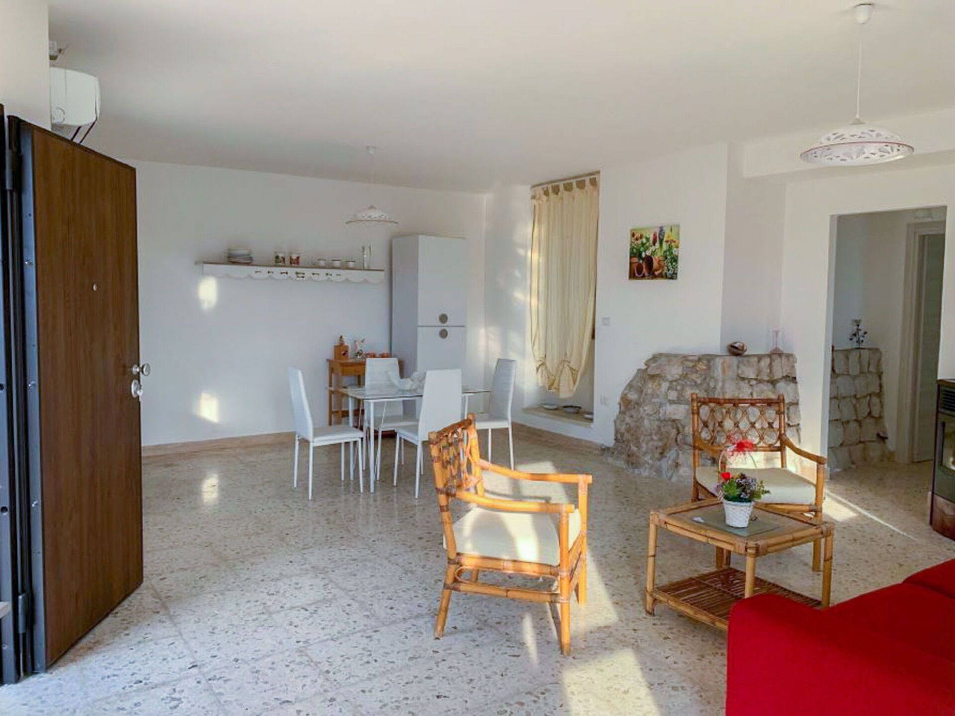 A spacious living area with a dining table, chairs, and a red sofa.