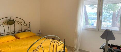A room with a bed, a window, and a lamp.