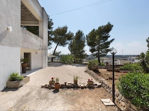 A modern building with a concrete facade, a paved courtyard, and potted plants. - Beautiful apartment for 4 guests with A/C, WIFI, TV, patio and pets allowed (Matino)