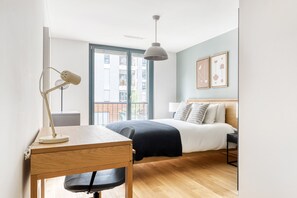 Relax in a stylish room with a made bed, desk, and city view.