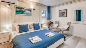 A hotel room with a bed, two chairs, a small table, and a window with curtains.