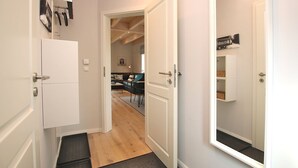 Un pasillo con una puerta blanca que da a una sala de estar con un sofá y una mesa de centro.