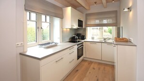 Una cocina moderna con armarios blancos, horno empotrado y un amplio ventanal que proporciona luz natural.