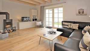 Una sala de estar moderna con chimenea, un sofá, una mesa de centro y vistas al exterior.