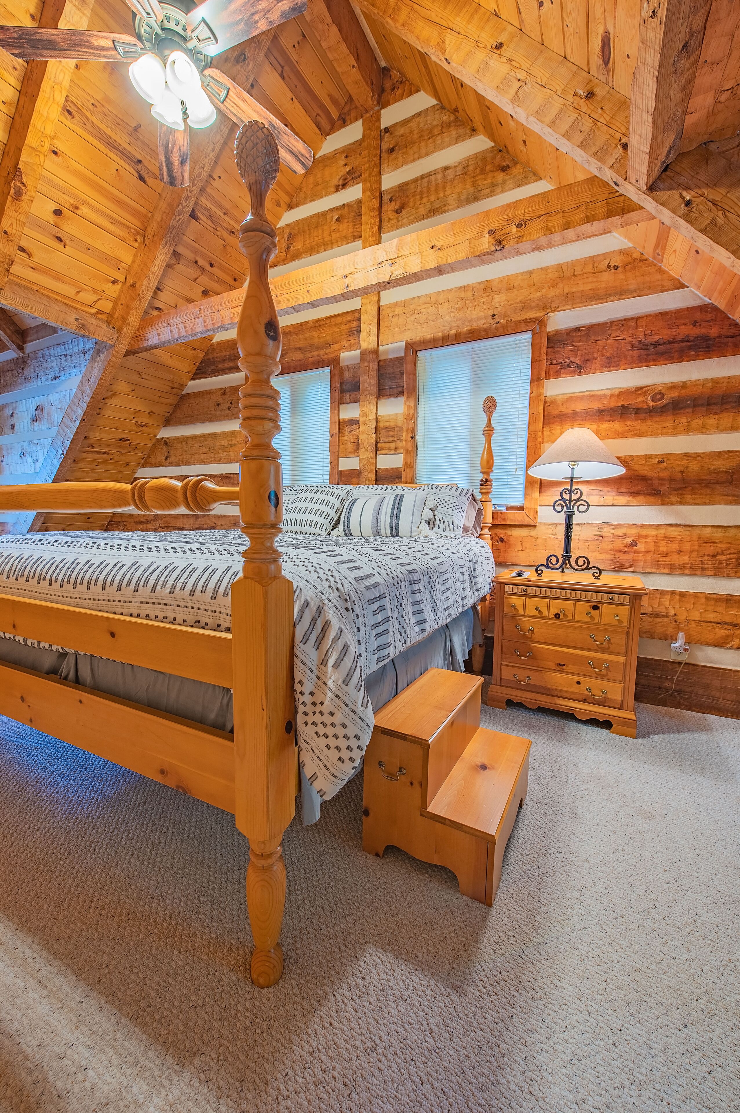 Ein Schlafzimmer aus Holz mit einem Himmelbett, einem Nachttisch und einer Lampe.