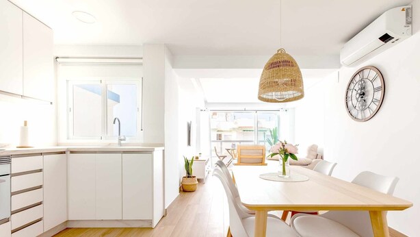 A modern kitchen with white cabinets, a wooden dining table, and a large clock on the wall. - A&n Santa Fé       . (Torre del Mar)