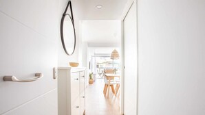 A narrow hallway with a white door, a wall-mounted circular mirror, and a hanging pendant light. - A&n Santa Fé       . (Torre del Mar)