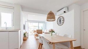 A modern kitchen with white cabinetry, a dining area with a wooden table and chairs, and a large window providing natural light. - A&n Santa Fé       . (Torre del Mar)