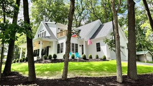 A two-story house with a front porch, a flag, and a well-maintained lawn.