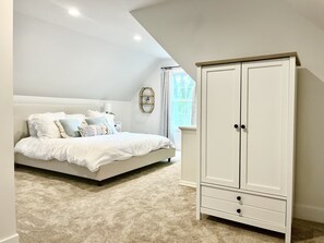 Une chambre à coucher avec un lit, une armoire et une fenêtre avec des rideaux.
