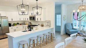 A modern kitchen with white cabinets, stainless steel appliances, and a central island with bar stools.