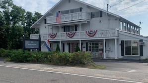 A two-story building with a balcony and a sign indicating it is a restaurant. - The Beach Rose Inn (Wells)