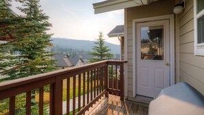 Une terrasse en bois avec une porte blanche et une vue sur une chaîne de montagnes.