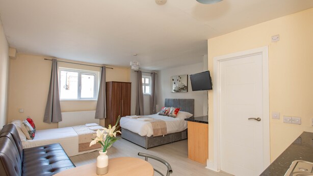 Une chambre d’hôtel de taille réduite comprenant un lit, un canapé, une table à manger et une kitchenette.