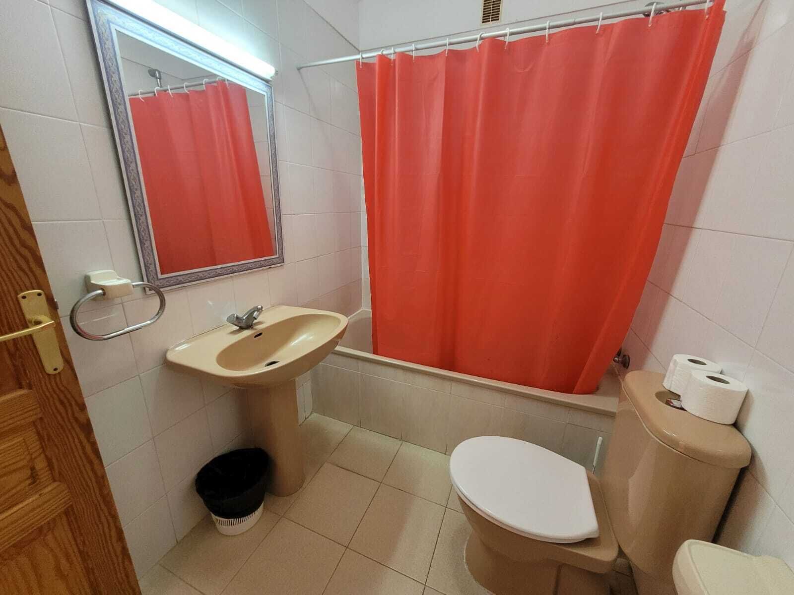 A bathroom with a sink, toilet, and shower curtain.