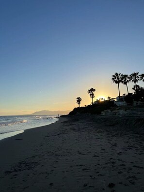 Relax on the wide beach, surrounded by palm trees and majestic mountains.