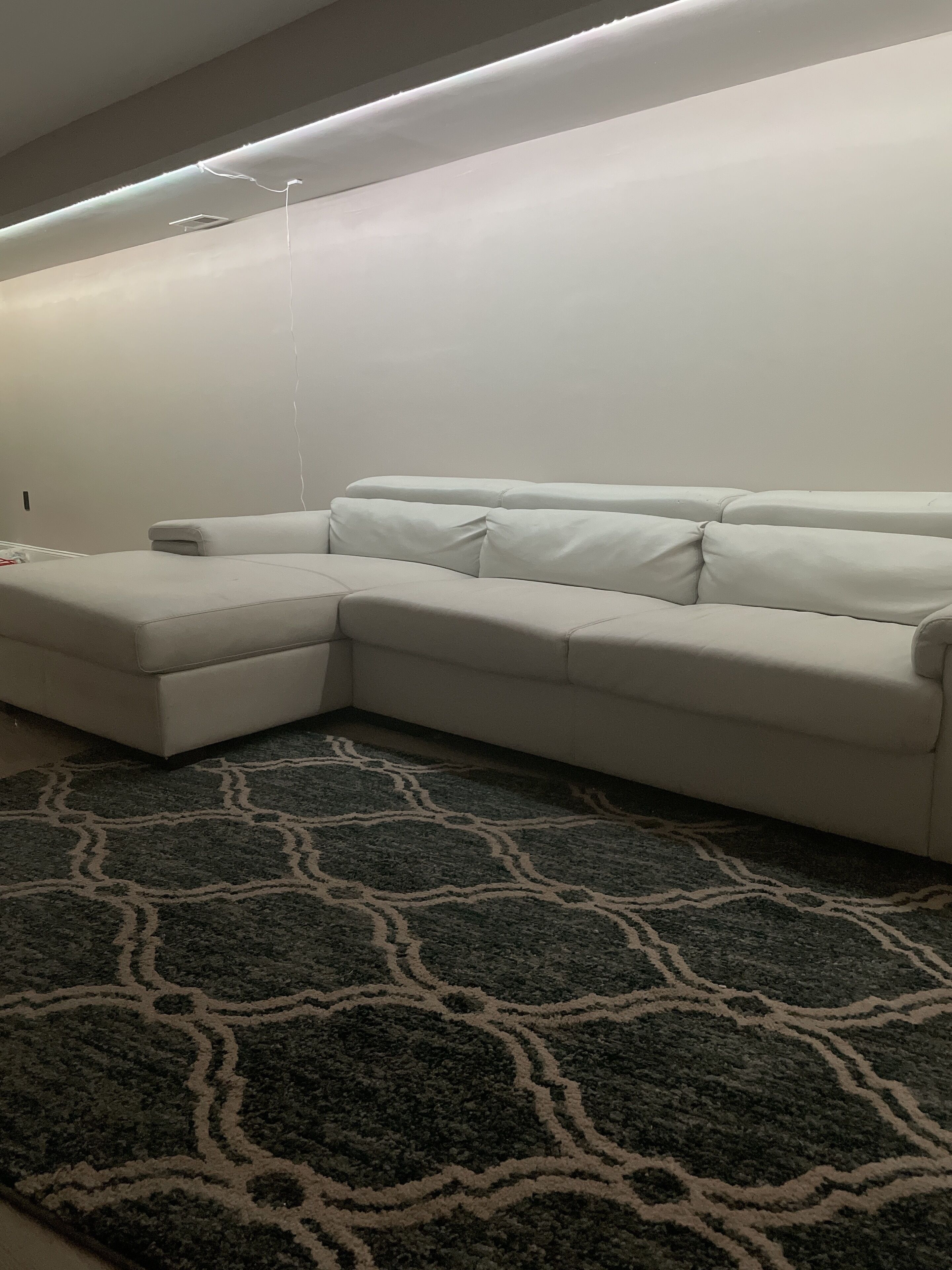 A white sectional sofa with a patterned rug.