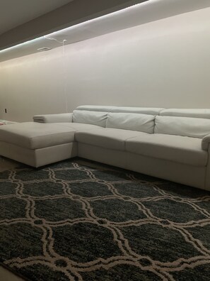 A white sectional sofa with a patterned rug.