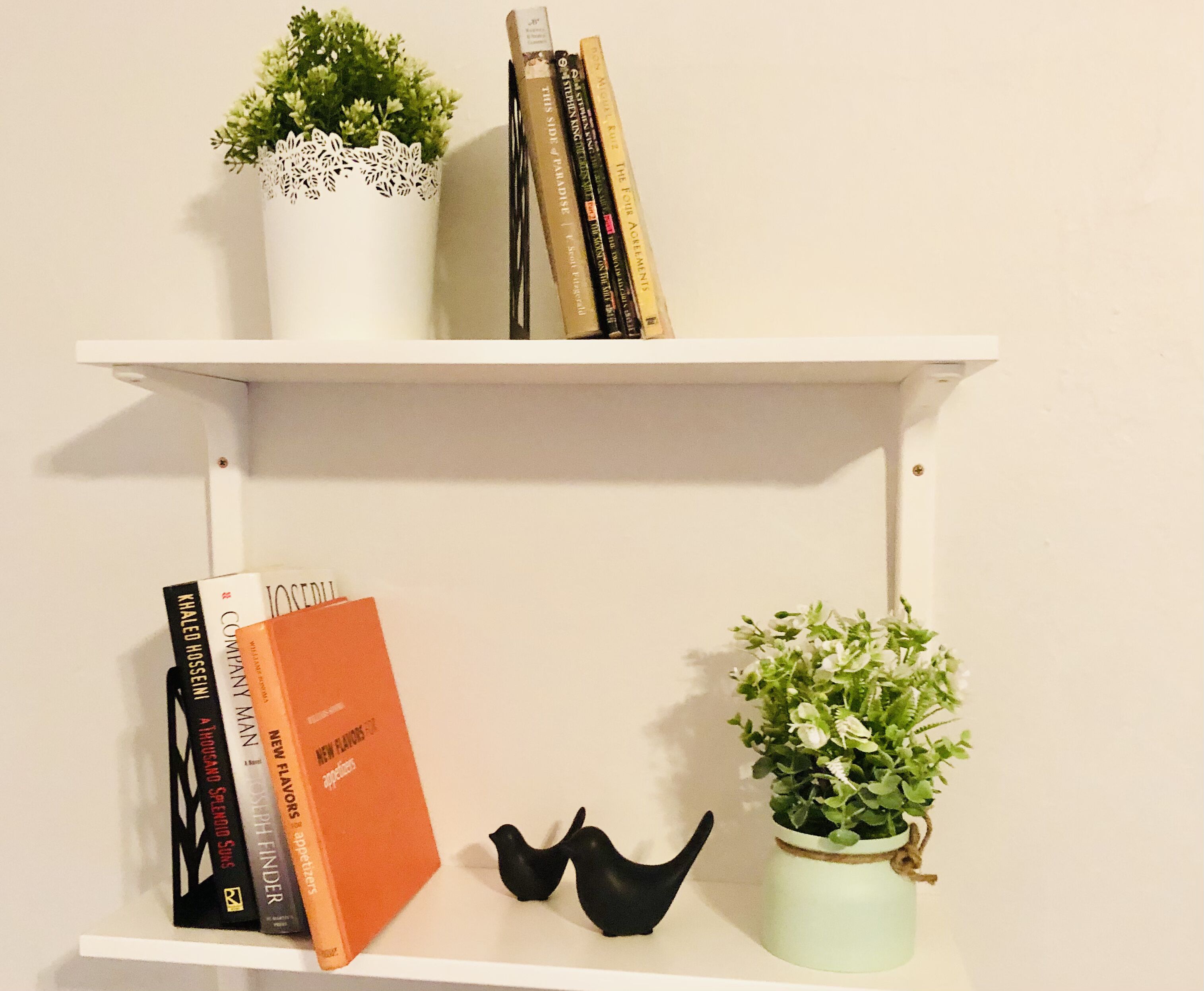 Een plank met boeken, een potplant en een decoratieve vogel.
