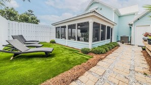 Een huis met een overdekt terras, een gazon en een pad van stenen.