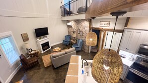 Un salon moderne avec une cheminée, un téléviseur et un coin repas, avec une cuisine en arrière-plan.