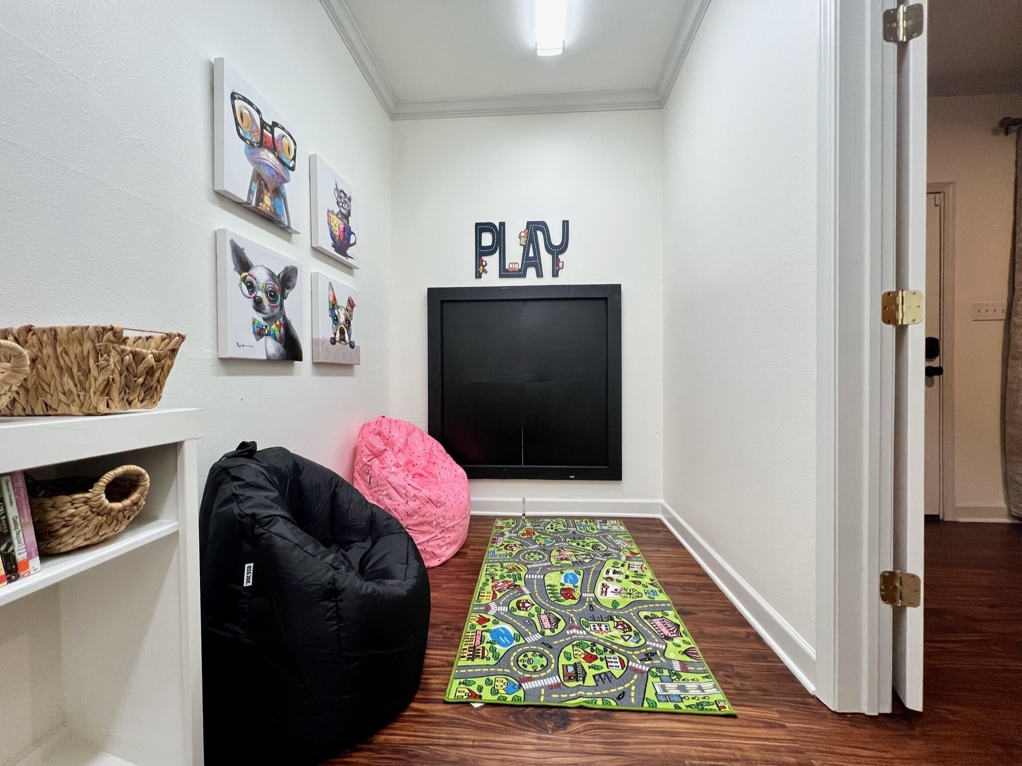 A hallway with a black bean bag chair, a colorful rug, and wall art including a 'PLAY' sign.