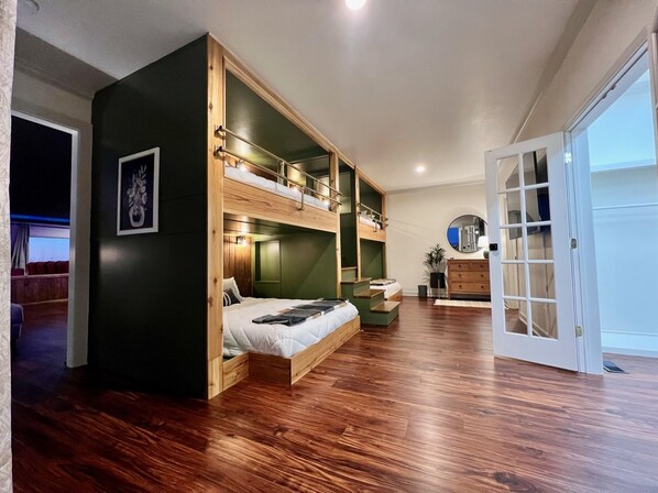 A room with a bunk bed, a dresser, and a mirror.