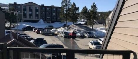 A parking lot with several cars and a snow-covered ground, surrounded by buildings.