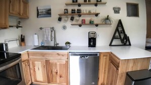 A kitchen with wooden cabinets, a stainless steel dishwasher, and a coffee maker on the countertop.