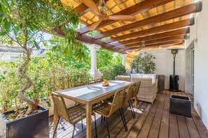 Relax in this serene outdoor patio area surrounded by lush greenery and a wicker sofa.