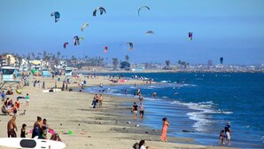 Une plage avec des gens, des cerfs-volants et une tour de surveillance des sauveteurs.