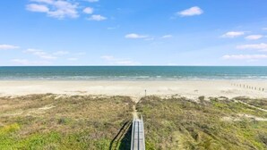 Ein Strand mit einer Holzpromenade, die zum Meer führt.
