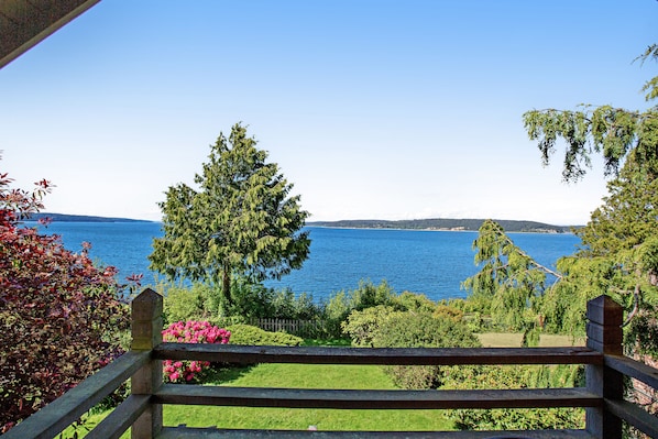 Una terraza de madera con vistas a un lago y colinas al fondo.