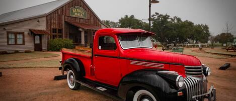 A vintage red truck parked in front of a rustic building with a sign that reads "HENLEY HALL".