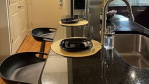 Une cuisine moderne avec des meubles en bois foncé, un réfrigérateur en acier inoxydable et un plan de travail en granit noir.