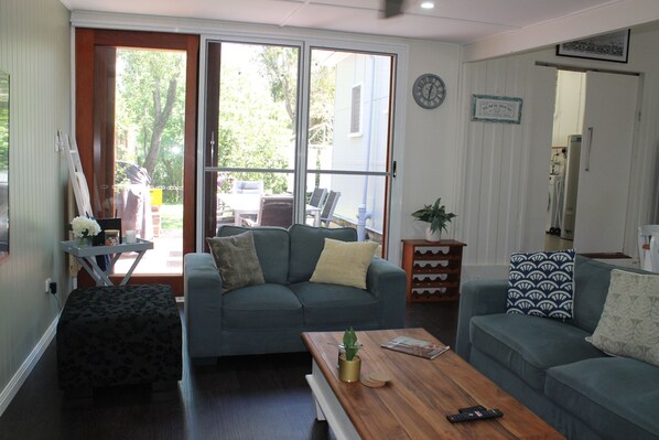 A living room with a sofa, a coffee table, and a small table with a plant.